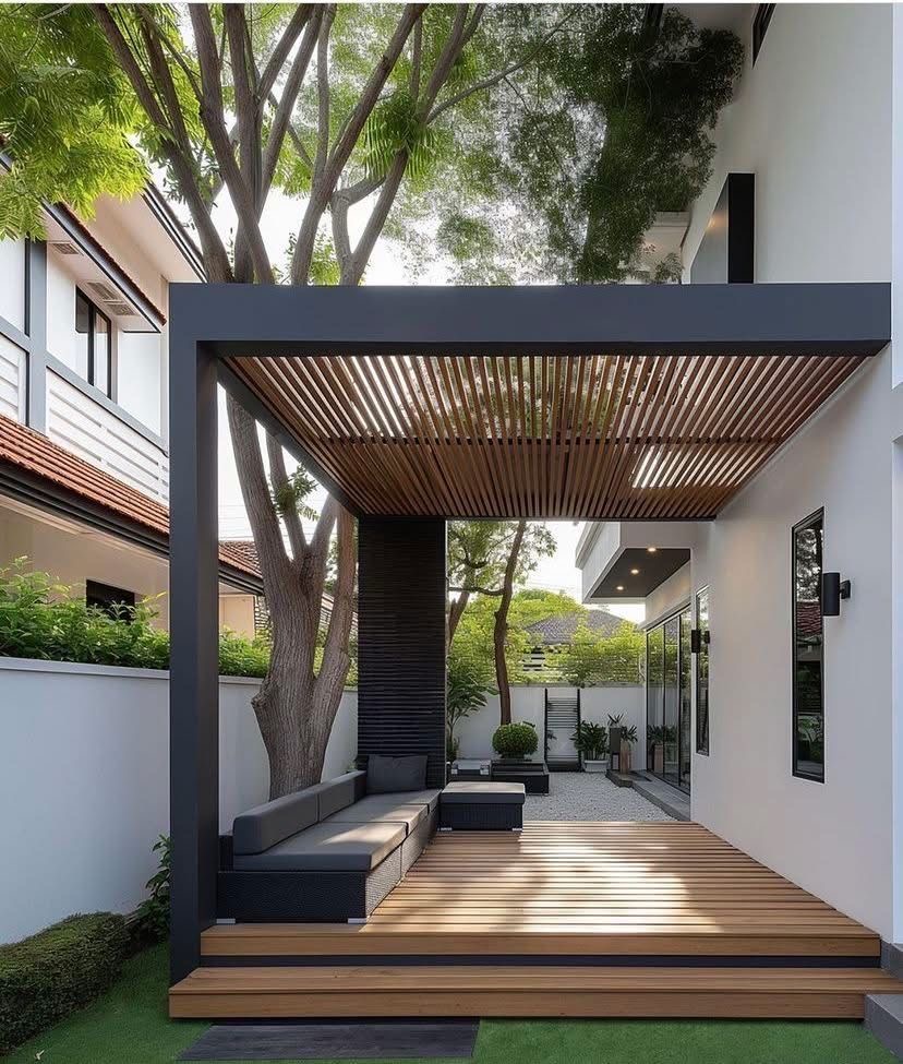 Mái pergola khung tối màu che góc hiên có sàn deck và ghế sofa ngoài trời